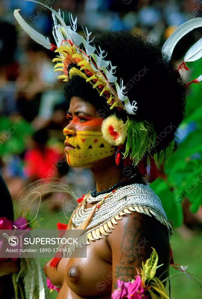 Bare-breasted native woman wearing a feathered headdress, beaded necklaces and face paints during a gathering of tribes at Mount Hagen in Papua New Gu...