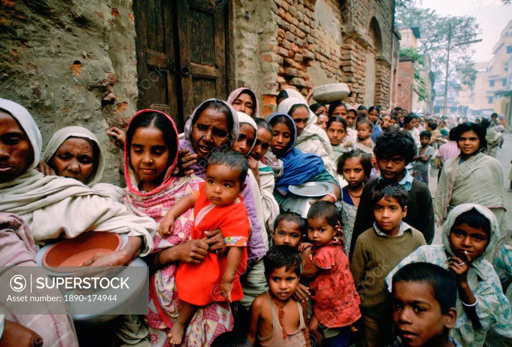 Women carrying pots with children in early morning food queue at Mother Teresa's Mission Calcutta, India