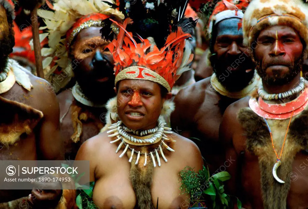 Bare-breasted tribeswoman and tribesmen wearing face paints, bone necklaces and feathered headdress during a gathering of tribes at Mount Hagen in Pap...