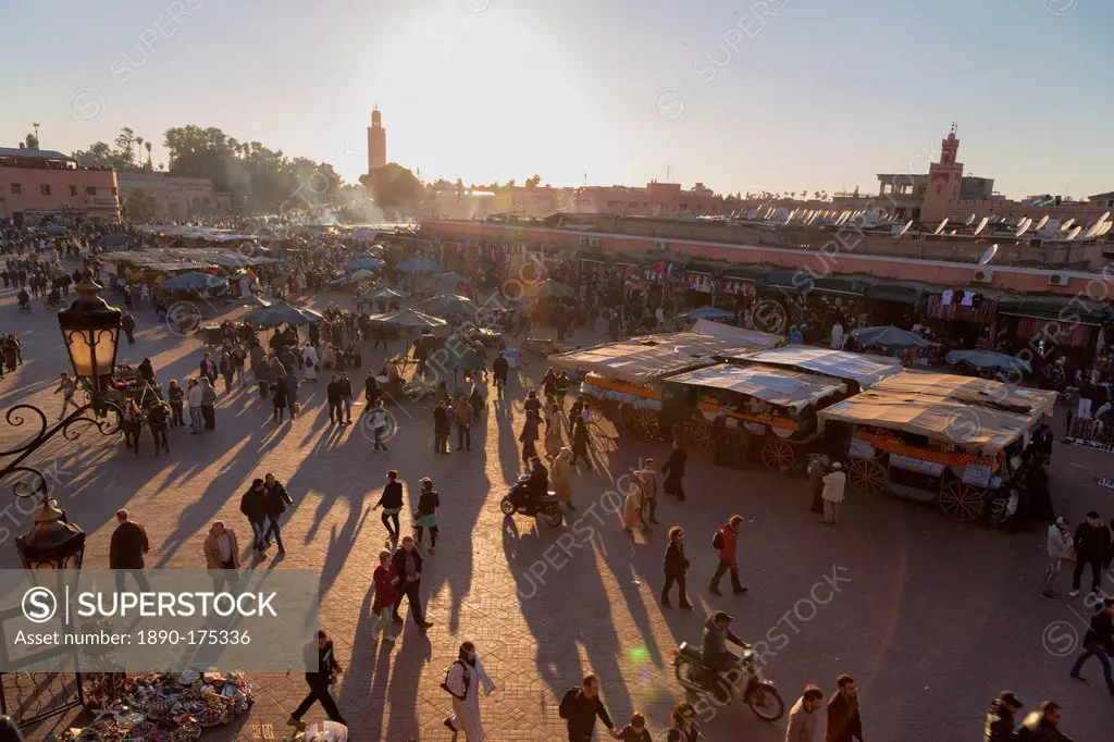 Evening light on the busy square of Place Jemaa el-Fna with the minaret of the Koutoubia Mosque in the distance, UNESCO World Heritage Site, Marrakech...