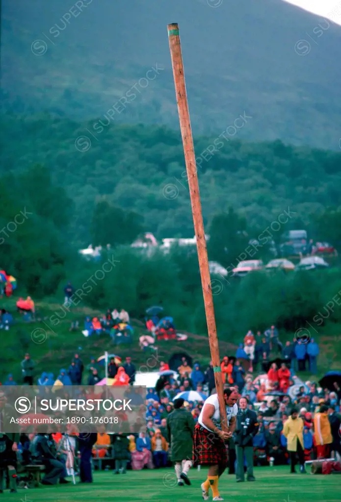 Tossing the Caber test of strength at the Braemar Games highland gathering in the rain in Scotland.