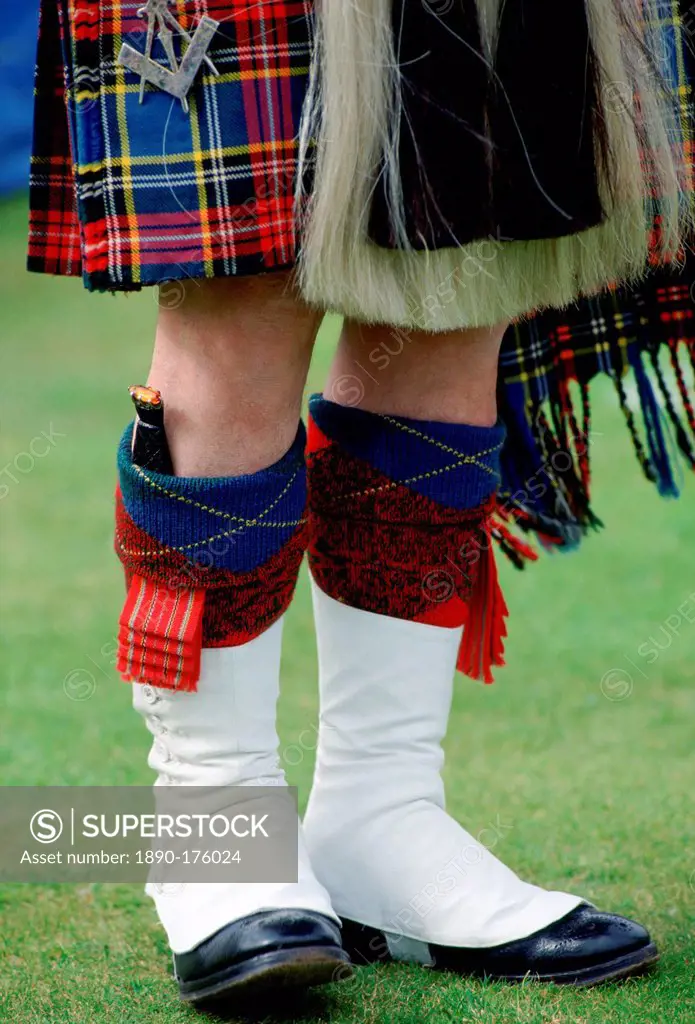 Scottish piper wearing tartan kilt, white gaiters, sporran and with dirk (knife) tucked in h is sock at the Braemar Games highland gathering in Scotla...