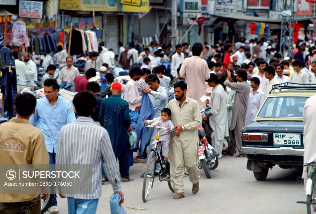 Man wheeling child on bicycle in crowded street in Islamabad in Pakistan