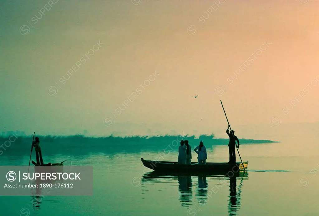 Man ferries passengers in a small boat, India