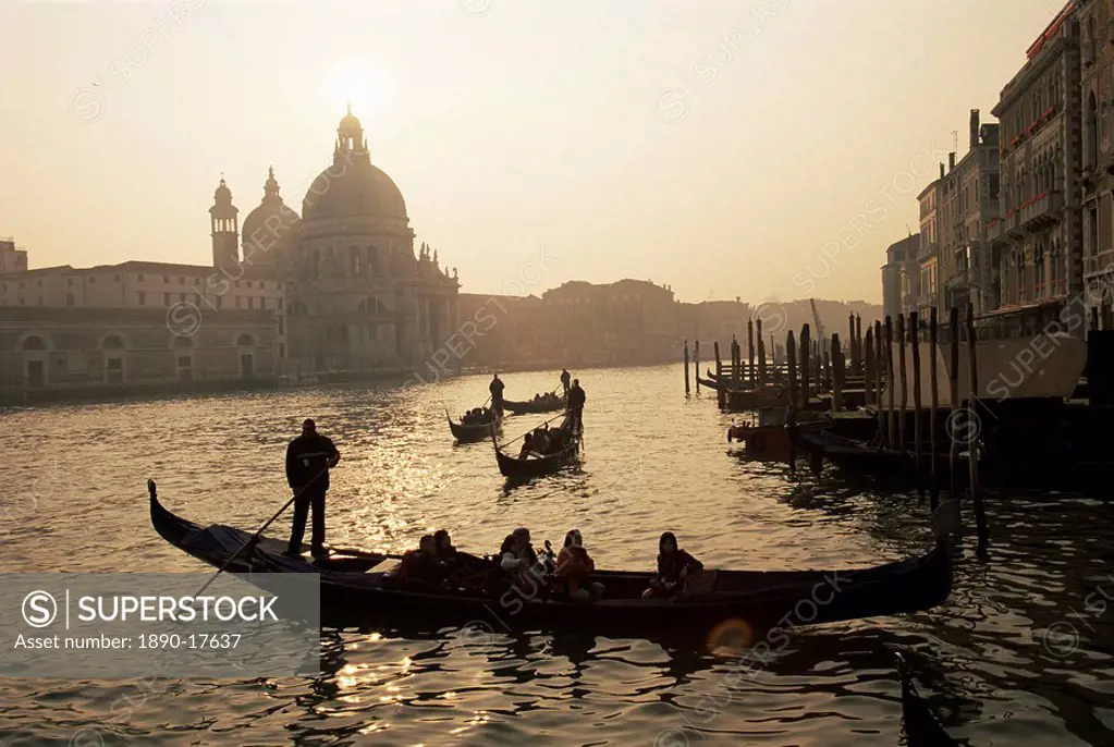 Sunset view along the Grand Canal to Santa Maria Della Salute church with gondoliers in silhouette, Venice, Veneto, Italy, Europe
