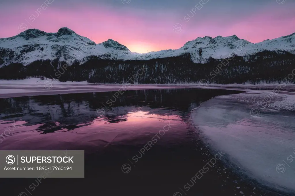 Colorful sky at sunrise on snowcapped mountains and frozen Lake Silvaplana, Maloja, Engadine, Graubunden canton, Switzerland, Europe