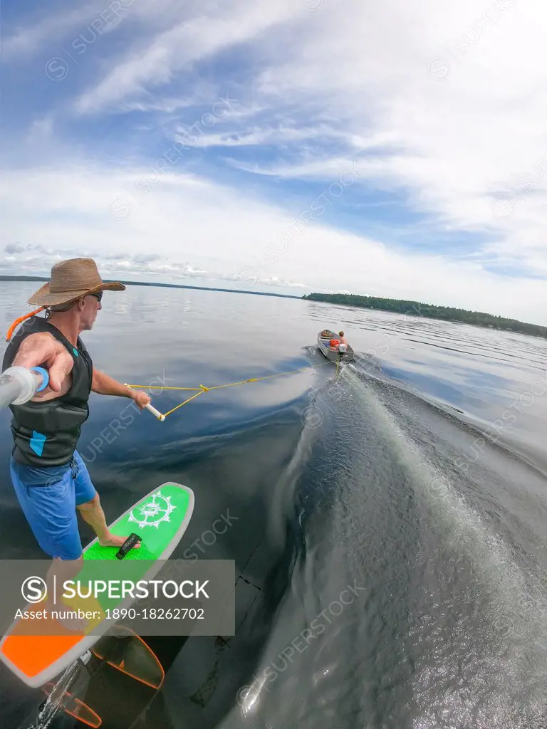Photographer Skip Brown rides his hydrofoil behind a small boat on Sebago Lake, Maine, United States of America, North America