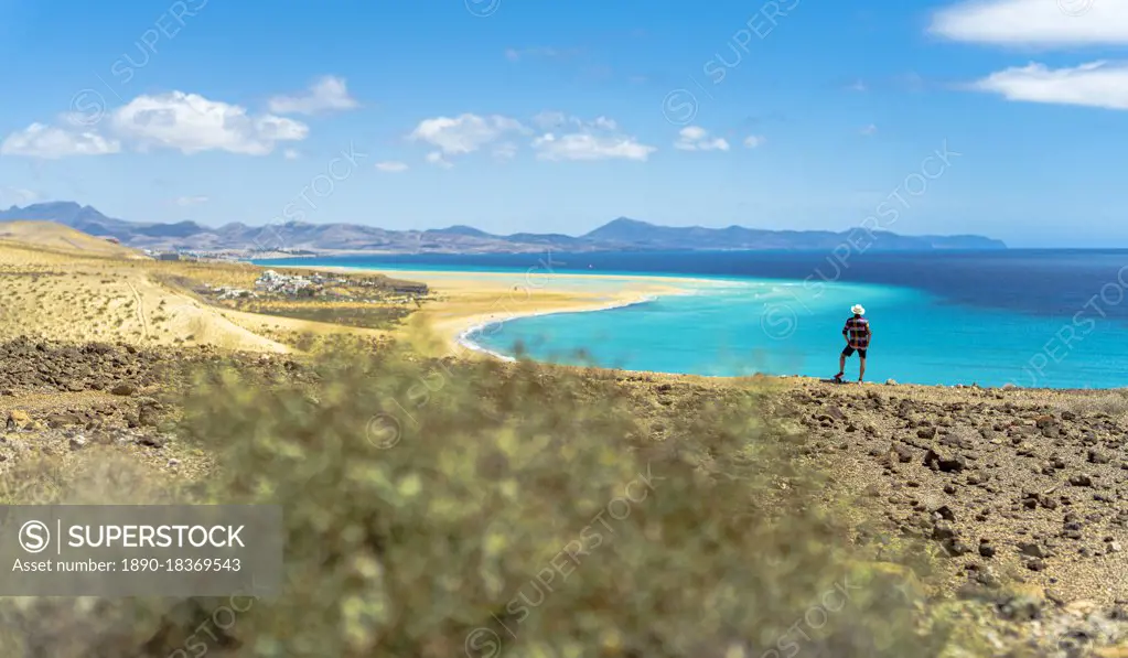 Tourist with straw hat looking at the ocean from Mirador Del Salmo viewpoint, Costa Calma, Fuerteventura, Canary Islands, Spain, Atlantic, Europe
