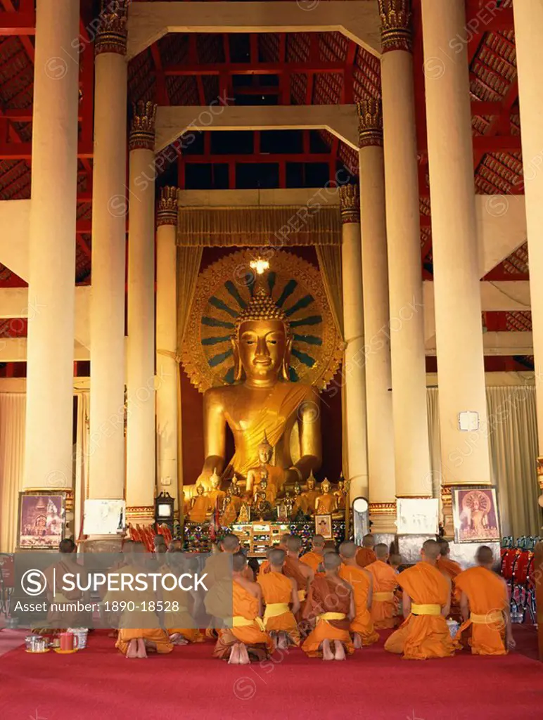 Monks in saffron robes kneel before a statue of the Buddha in Wat Phra Sing in Chiang Mai, Thailand, Southeast Asia, Asia