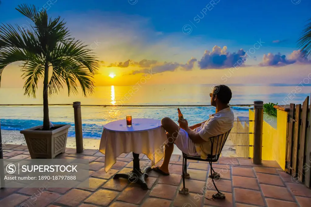 Man enjoying a beverage on a patio at sunset in Turks and Caicos Islands, Atlantic, Central America