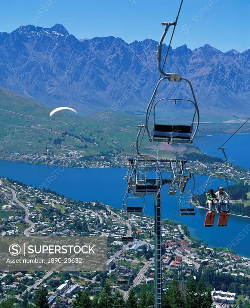 Tourists on a chair lift with Lake Wakatipu, the Remarkable Mountains and Queenstown, South Island, New Zealand, Pacific