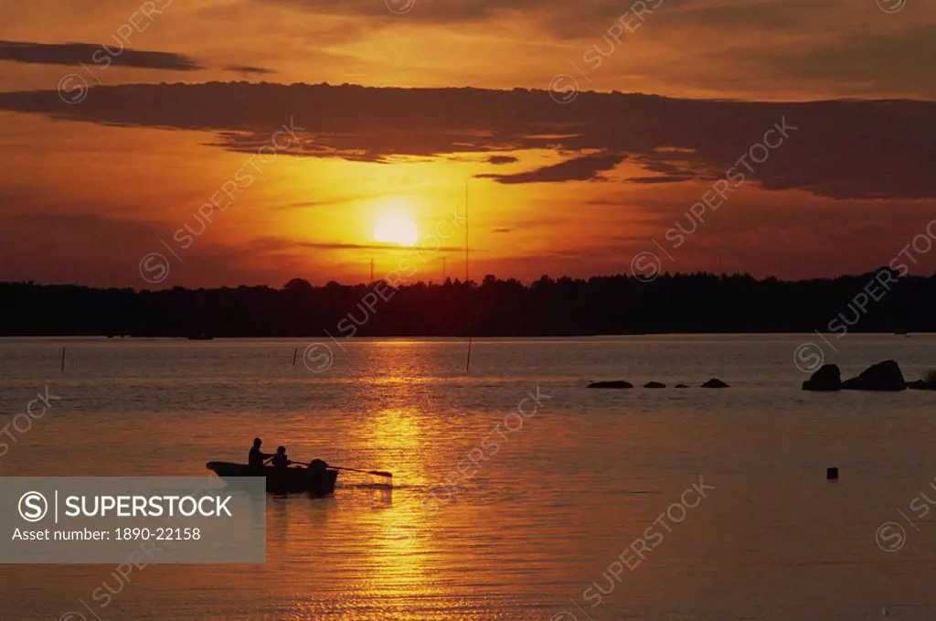 Row boat silhouetted over Dragso bay at sunset in summer, at Karlskona, Sweden, Scandinavia, Europe