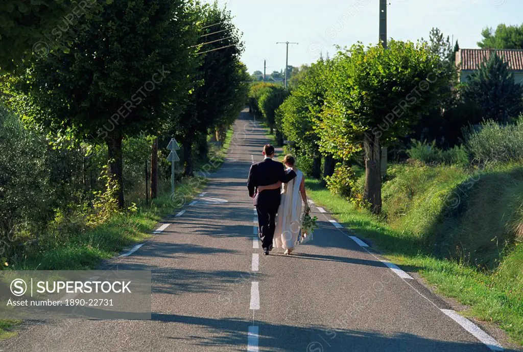 Newly_wed bride and groom walk from village church to reception, Provence, France, Europe