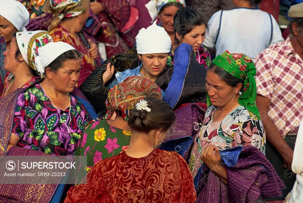 Women in bright dresses and head scarves in the new clothes market within the Old City wall of Bukhara, Uzbekistan, Central Asia, Asia