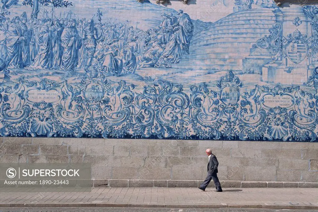 Man walks by the azulejo tile panel of the Carmo church in Oporto, Portugal, Europe