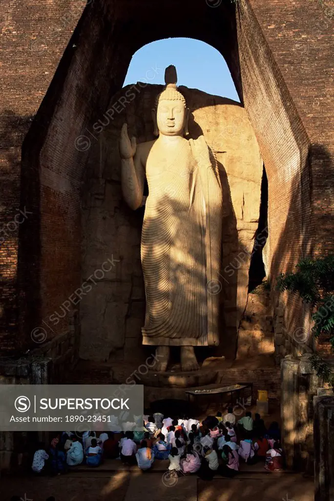 Pilgrims seated in front of the 39 ft high standing Buddha, Aukana, Sri Lanka, Asia
