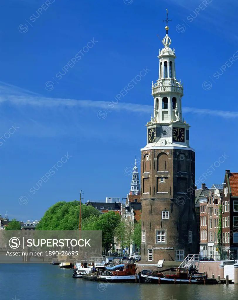 Boats on the canal beside a tower, the Montelbaanstoren, in Amsterdam, Holland, Europe