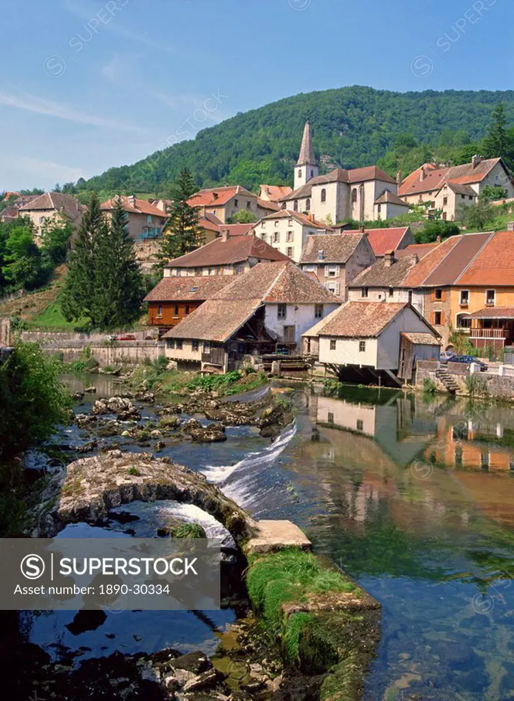 The weir and remains of a medieval bridge on the River Loue, with the houses and church of the village of Lods in Franche_Comte, France, Europe