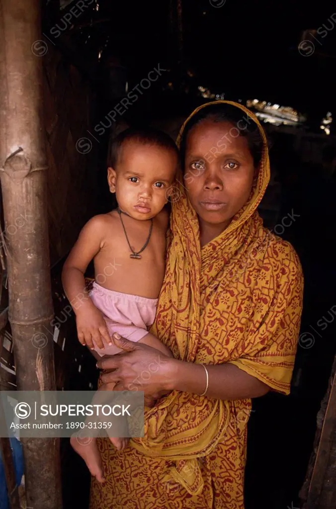 Portrait of a Bangladeshi mother in a sari holding her young child, looking at the camera, in a slum in Dhaka, Bangladesh, Asia