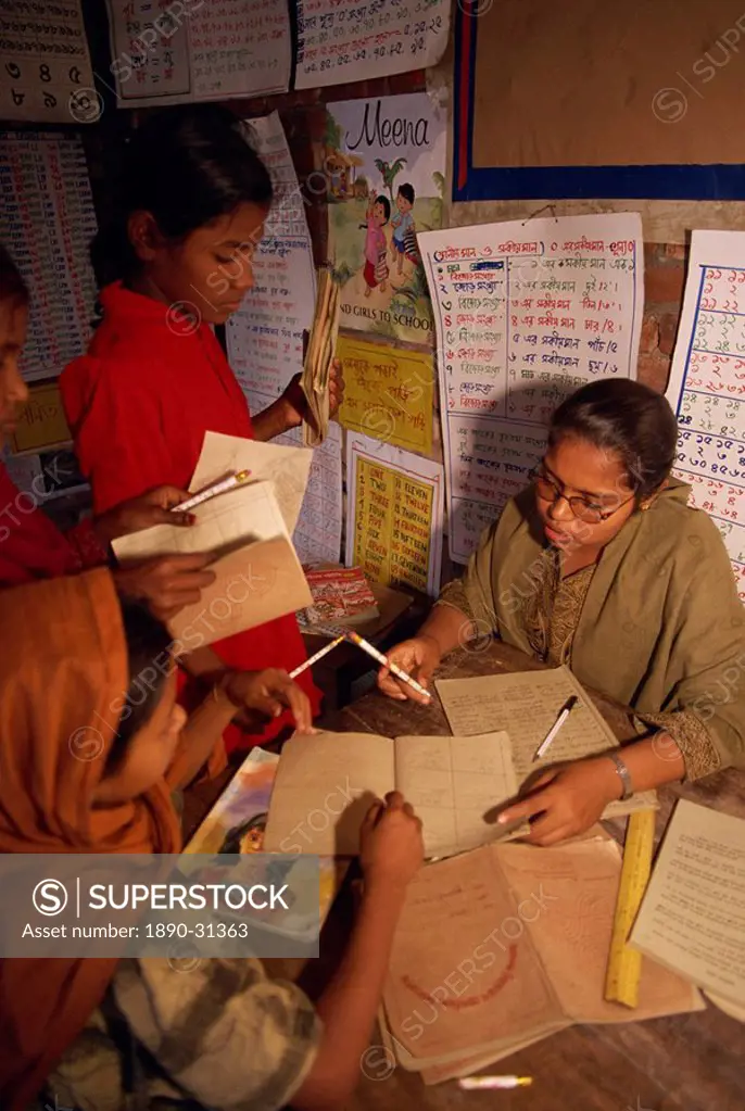 A Bangladeshi woman teacher marks students books in a school in the slums of Dhaka Dacca, Bangladesh, Asia