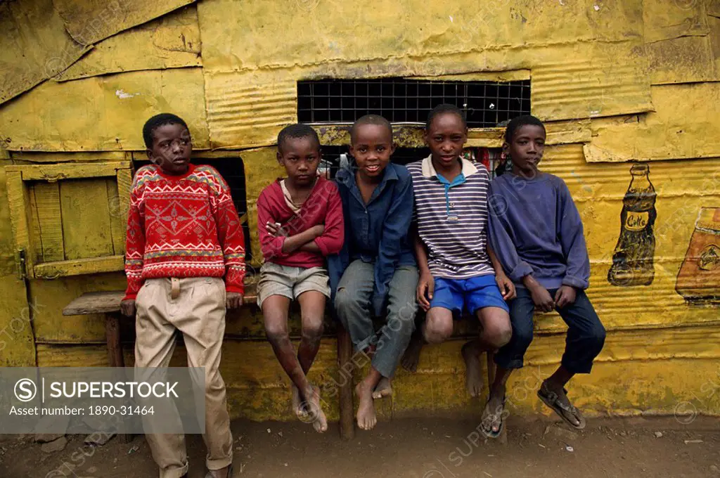 Portrait of a group of five boys, slum children, sitting on a bench outdoors, looking at the camera, Kariobangi, Nairobi, Kenya, East Africa, Africa