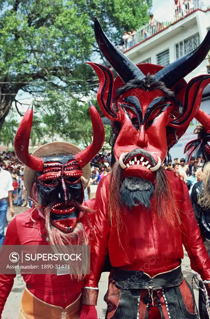 Portrait of two people with devil masks, wearing red, looking at the camera, during Easter celebrations at Ciudad Santos in Mexico, North America