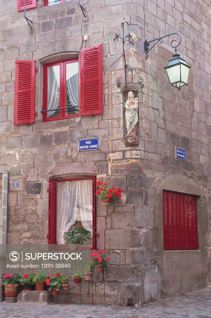 Statue of the Madonna and Child on a house with red shutters on a street corner in Besse en Chandesse, in the Auvergne, France, Europe