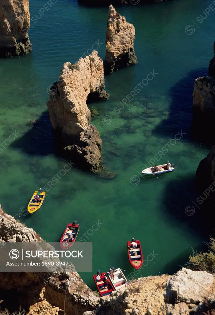 Aerial view of small boats in the sea alongside sea stacks and rock formations along the Atlantic coast of the Algarve, Portugal, Europe