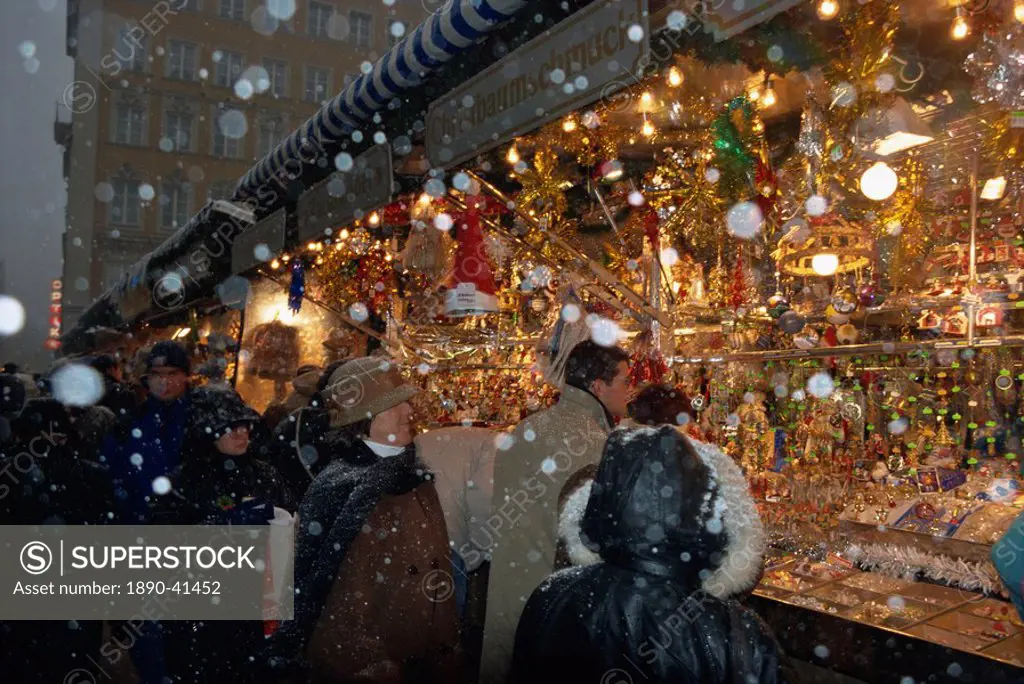 People shopping as snow falls at a Christmas market stall, Marienplatz, Munich, Bavaria, Germany, Europe