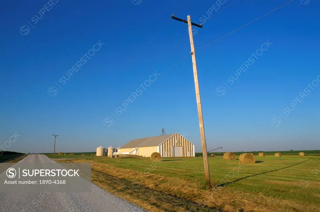 Telegraph pole and flat farm landscape with barn, in Hudson, Midwest, Illinois, United States of America, North America