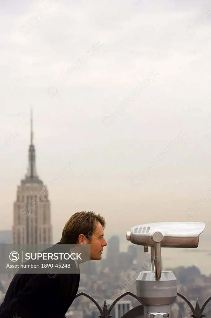Business man at Rockefeller Center looking through telescope, New York, United States of America, North America