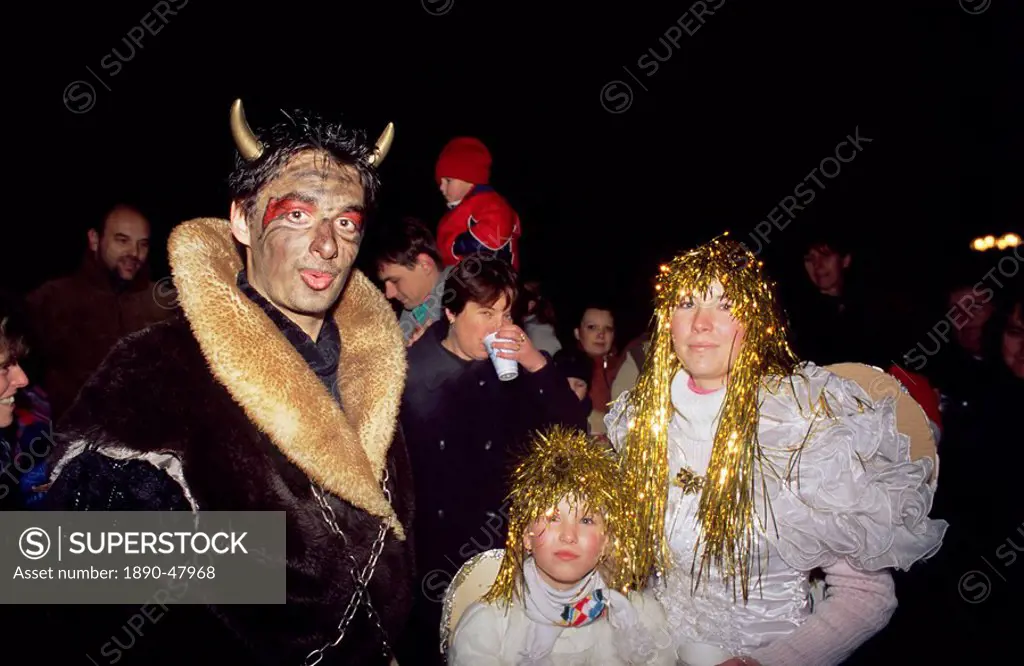 People dressed up as the devil and two angels on the streets of the Old Town on eve of St. Nicholas Day, 5th December, giving children sweets, Stare M...