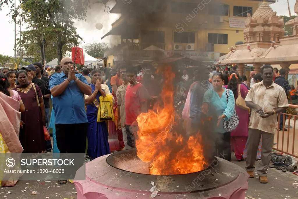 Pilgrims praying and throwing offerings into holy fire during the Hindu Thaipusam Festival at Sri Subramaniyar Swami Temple, Batu Caves, Selangor, Mal...