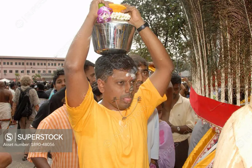 Pilgrim known as kavadi carrier with pierced tongue, during the Hindu Thaipusam Festival, carrying container paal kudam of milk offerings from Sri Sub...