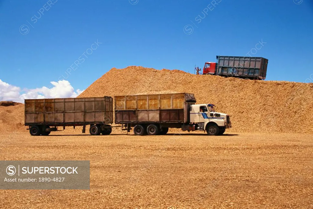 Trucks and trailers at the wood chip stocks at the port awaiting export at Puerto Montt in the Lake District of Chile, South America