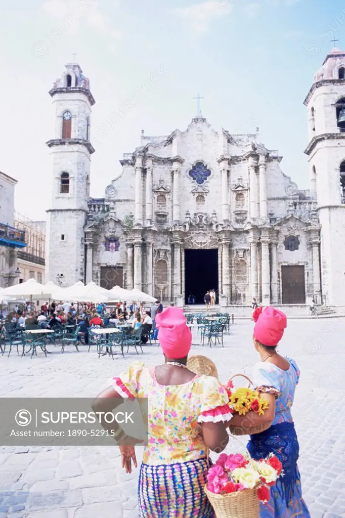 Two women in traditional clothing looking at San Cristobal cathedral, Havana, Cuba, West Indies, Central America