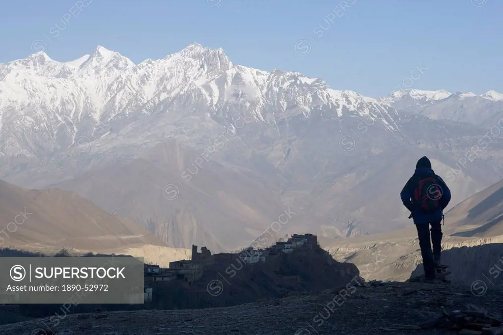 Trekker at dawn looking out over the old fortified village of Jharkot on the Annapurna circuit trek, the valley below is supposedly the deepest in the...