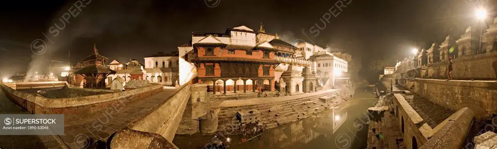 Smoke from funeral pyres on the ghats on the left drifts across the bridge over the river Bagmati at Nepal´s holiest Hindu pilgrimage site, Pashupatin...