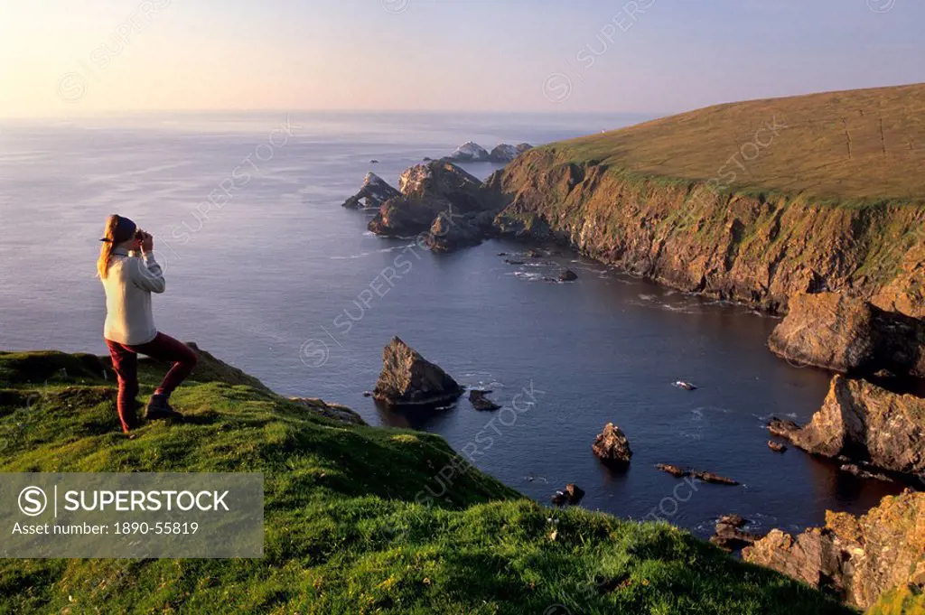 Birdwatching on cliffs of Hermaness Nature Reserve, looking north towards Vesta Skerry, Tipta Skerry gannetry, Muckle Flugga and its lighthouse in the...