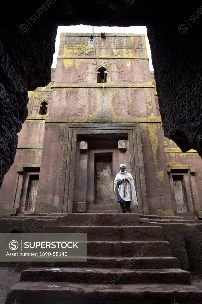 A priest stands at the entrance to the rock_hewn church of Bet Giyorgis St. George, in Lalibela, UNESCO World Heritage Site, Ethiopia, Africa