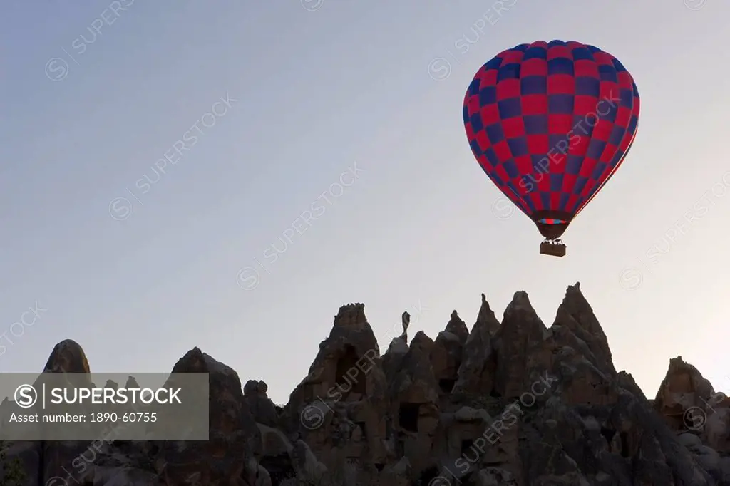 Hot air balloon taking off with tourists on board for a flight over the famous volcanic tufa rock formations around Goreme, Cappadocia, Anatolia, Turk...