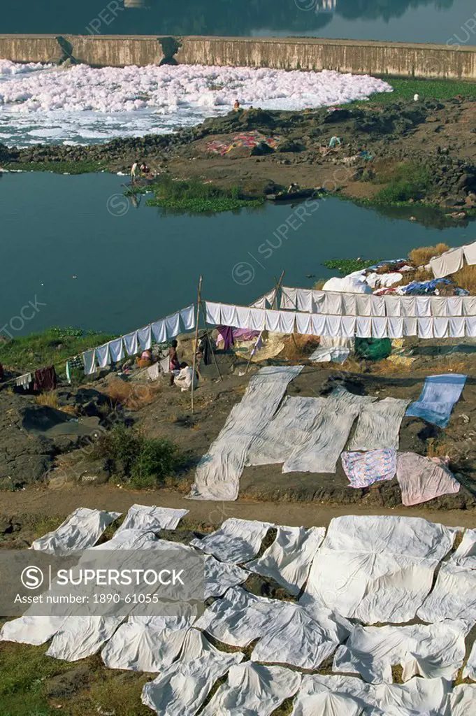 Laundry drying by the Mula River, with foam from detergent pollution beyond, Pune, Maharashtra state, India, Asia