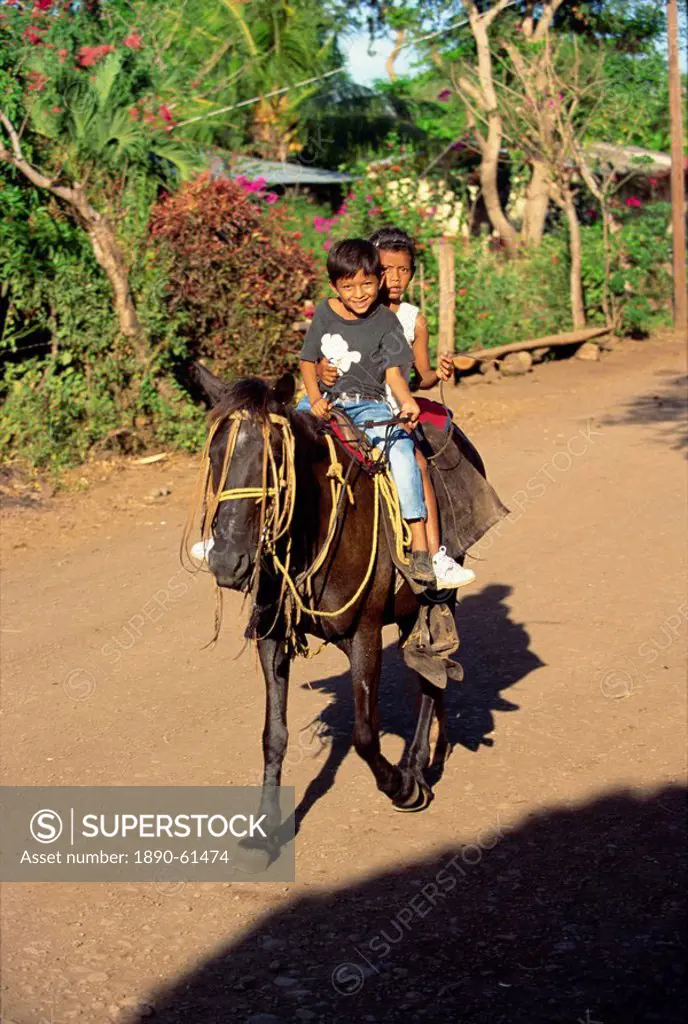 Two children on horseback at Balgue on the slopes of Volcan Maderas in the east of the island of Omotepe, Lake Nicaragua, Nicaragua, Central America