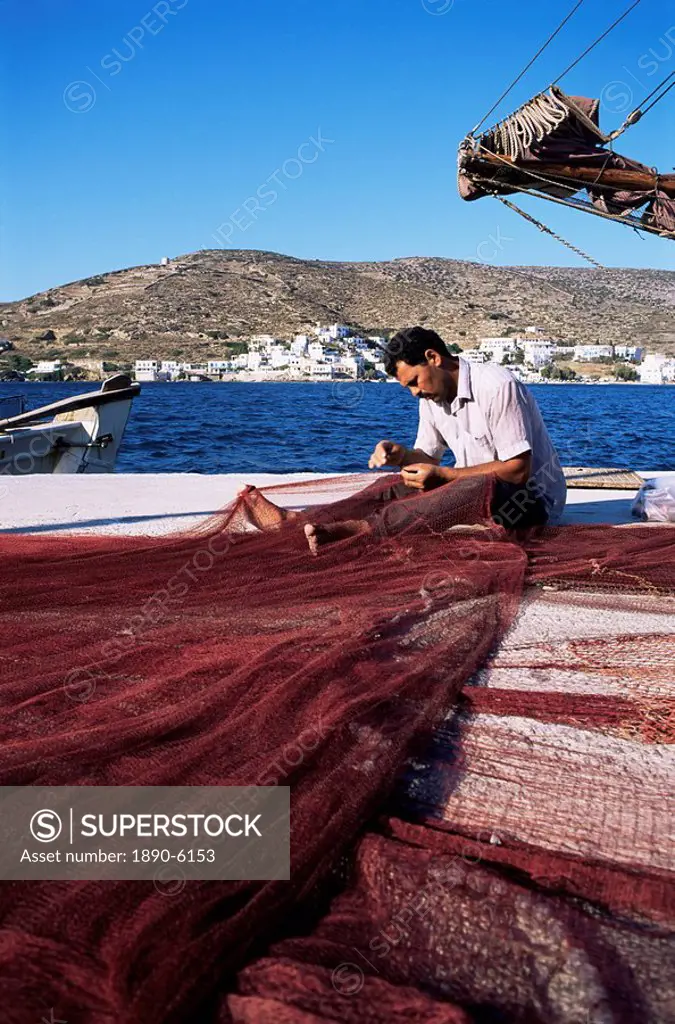 Fisherman mending nets on quayside at Katapola, island of Amorgos, Cyclades, Greece, Europe