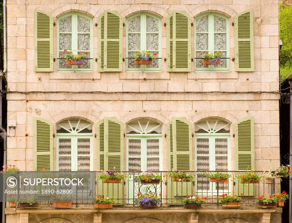 Colourful green wooden shutters and flower covered balcony on old stone building in Dinan, Brittany, France, Europe