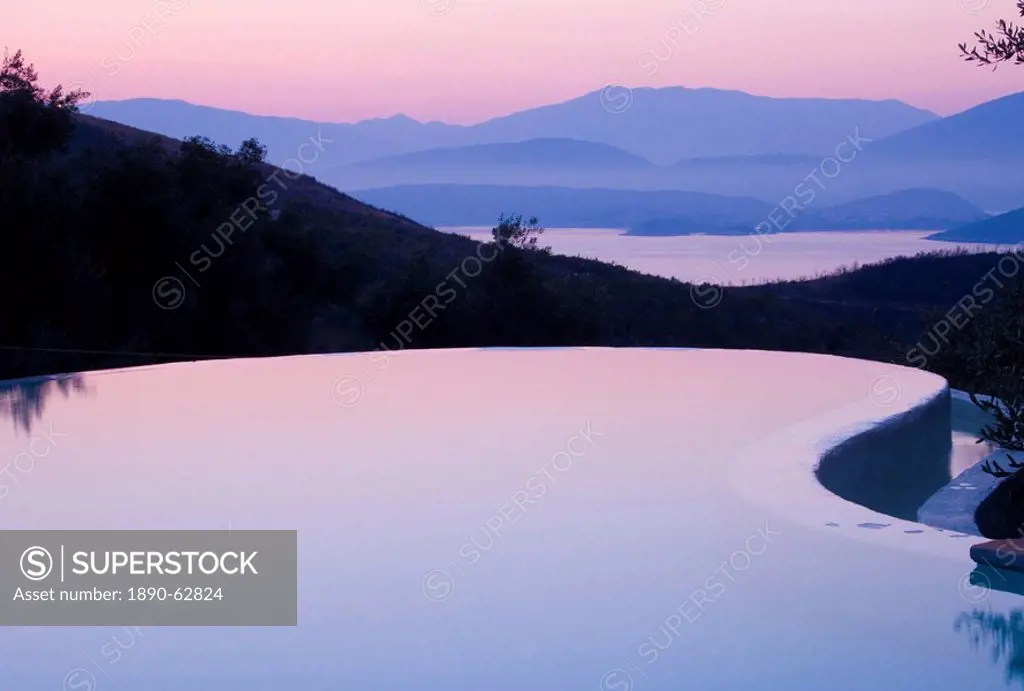 An infinity pool reflecting the sky at sunrise and the mountains of Albania across the Ionian Sea from Ayios Stefanos, Corfu, Ionian Islands, Greek Is...