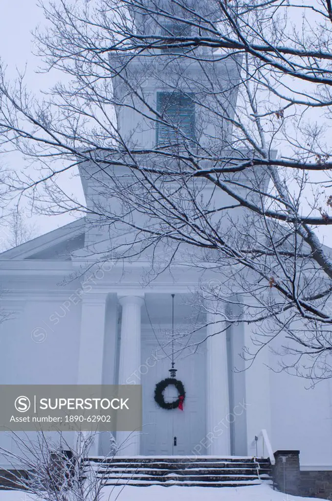 A traditional style wooden church with a Christmas wreath on the front door surrounded by snow, Rensselaerville, New York State, United States of Amer...