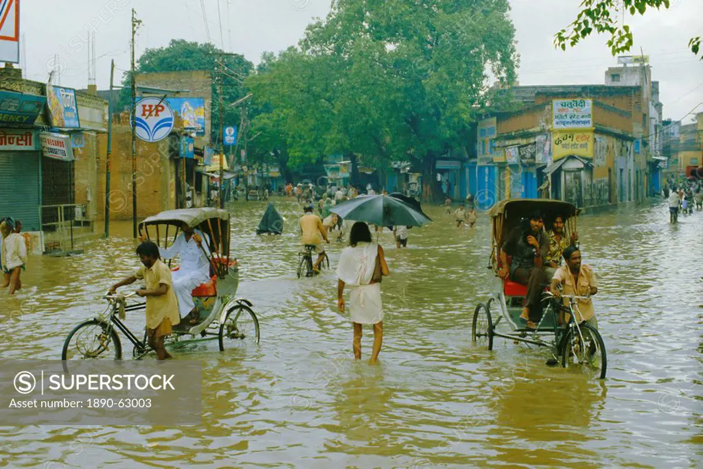 Rickshaws being pushed through the monsoon floods in a town, India