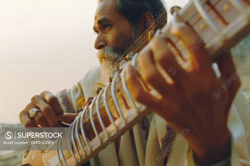 Elderly man playing the sitar beside the Ganges Ganga River, Varanasi Benares, Uttar Pradesh State, India