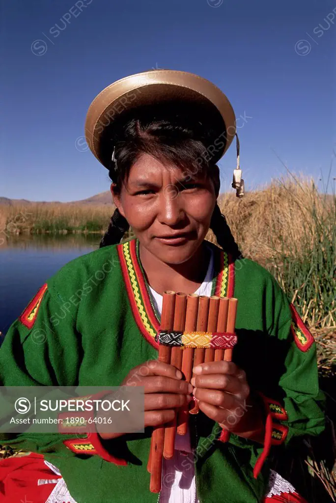 Head and shoulders portrait of a Uros Indian woman holding pipes, on floating reed island, Islas Flotantes, Lake Titicaca, Peru, South America